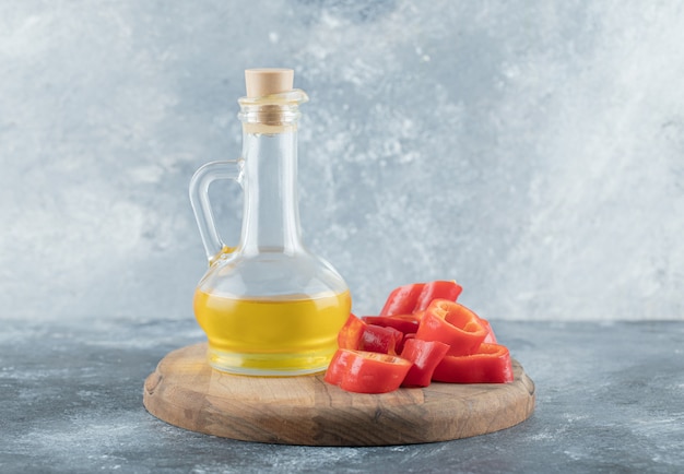 Sliced of sweet bell red pepper with a glass bottle of oil on a wooden board. 