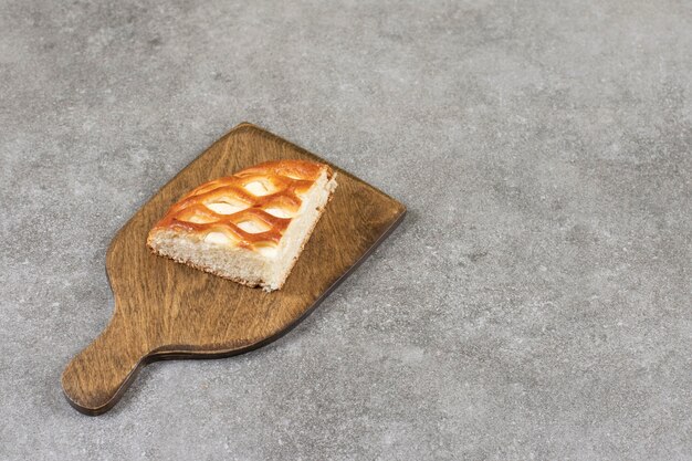Нарезанный сладкий хлеб на разделочной доске, на мраморном столе.