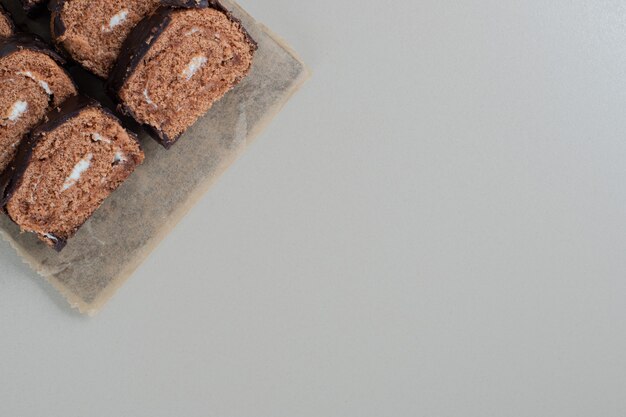 Нарезанный сладкий шоколадный рулет на деревянной доске.