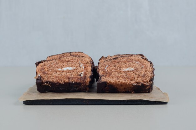 Sliced sweet chocolate roll on a wooden board .