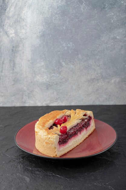 Sliced tasty cheesecake with berries placed on red plate.