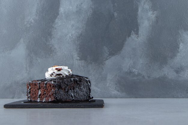 Sliced of tasty chocolate brownie with cream on cutting board. High quality photo