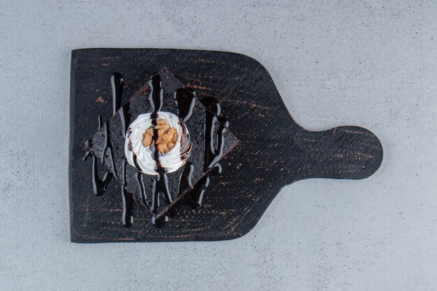 Sliced of tasty chocolate brownie with cream on cutting board