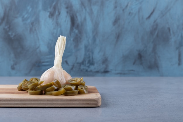 대리석 배경에 커팅 보드에 마늘을 얹은 얇게 썬 토마토.