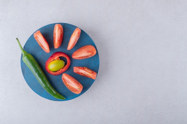 Foto gratuita pomodori a fette e peperoncino su un piatto sul tavolo di marmo.