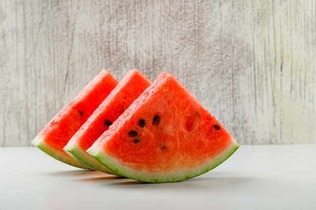 Free photo sliced watermelon side view on white and grunge background