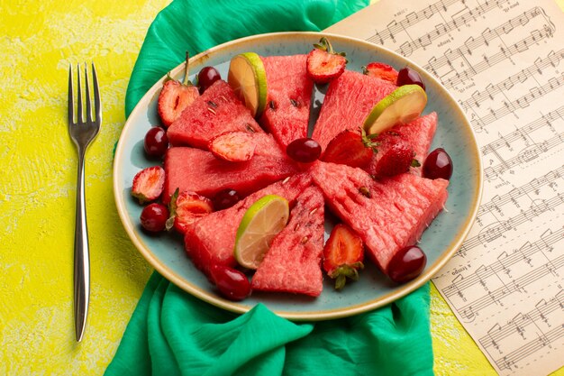 sliced watermelon with lemon strawberries on yellow