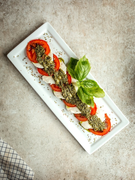 Foto gratuita formaggio bianco a fette e pomodoro con erbe