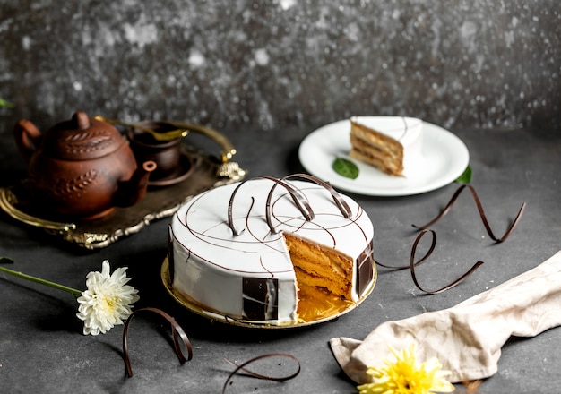 チョコレート片で飾られた白い艶をかけられたケーキをスライス