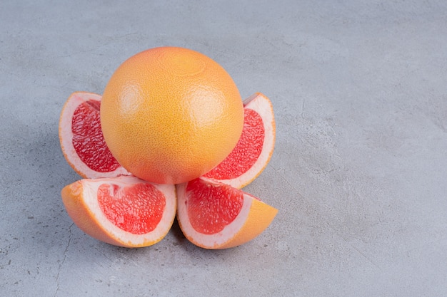 Sliced and whole grapefruits displayed on marble background. 