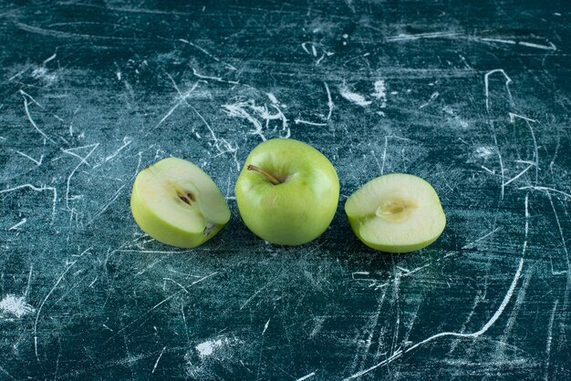 Sliced and whole green apples on marble table. 