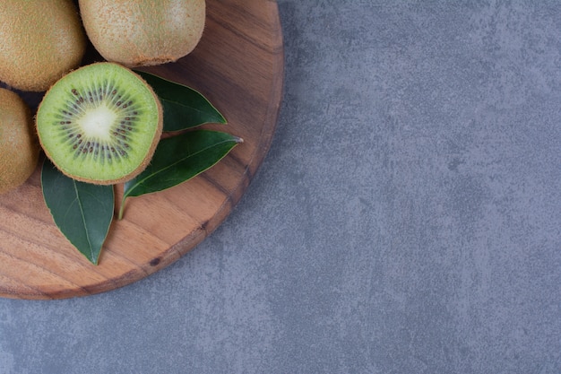 Sliced and whole kiwi fruits on board on the dark surface