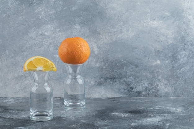 Free photo sliced and whole orange on top of empty glass.