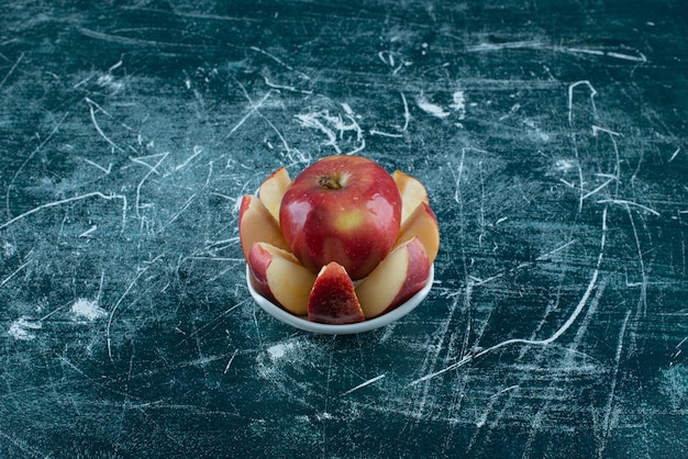 Free photo sliced and whole red apple in white bowl.