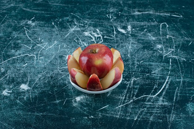 Sliced and whole red apple in white bowl. 