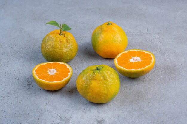 Sliced and whole tangerines arranged on marble background