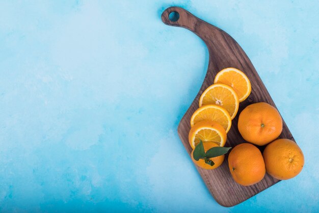 Free photo sliced yellow oranges on a wooden platter on blue