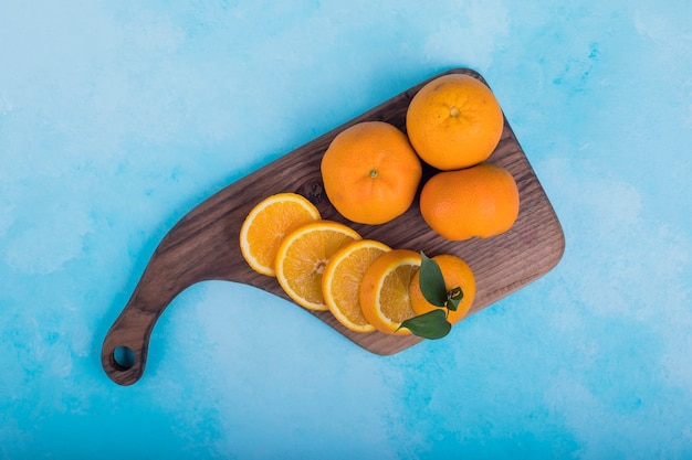 Sliced yellow oranges on a wooden platter, top view. 