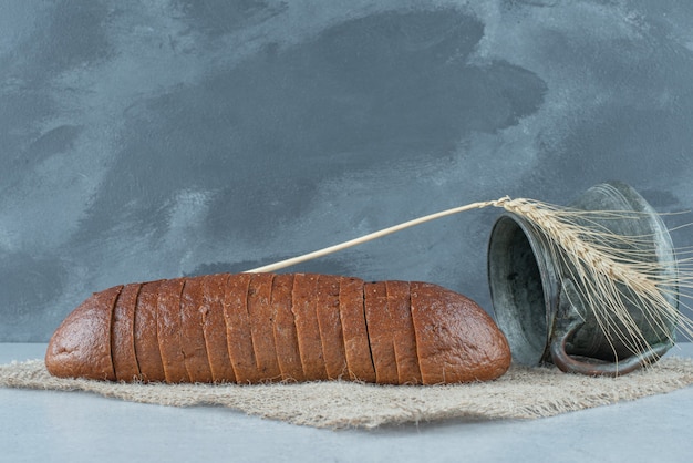 Free photo slices of black bread and antique mug on burlap