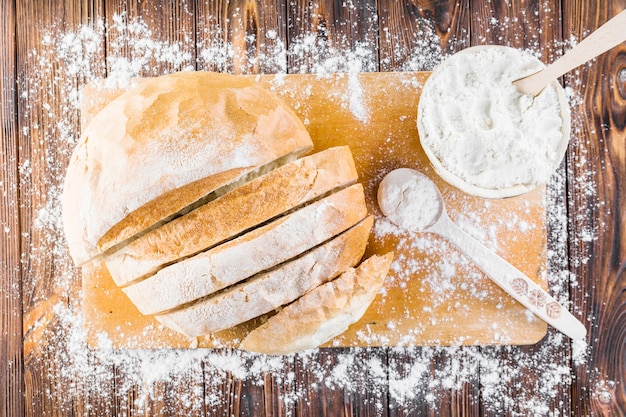 Slices of bread loaf over the wooden chopping board spread with flour