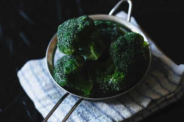  Slices broccoli in a colander on black background.