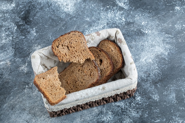 Slices of brown bread on a basket on a gray surface.