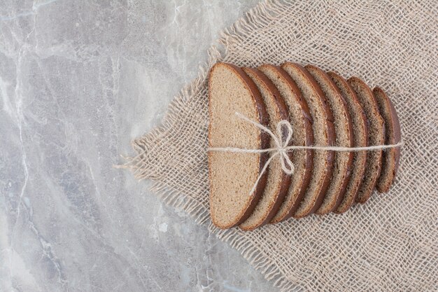 Slices of brown bread in rope on marble surface