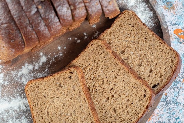 Fette di fette di pane integrale sul piatto di legno.