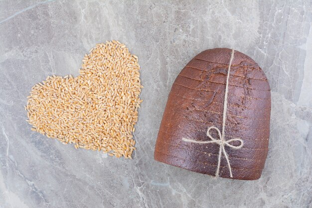 Slices of brown bread with oat grains on marble surface