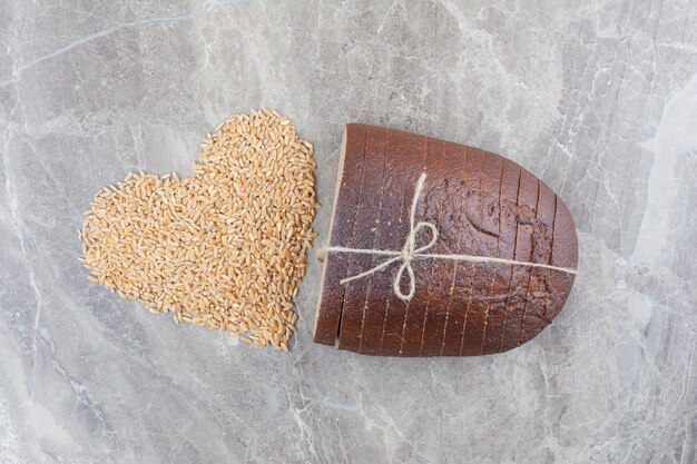 Slices of brown bread with oat grains on marble surface