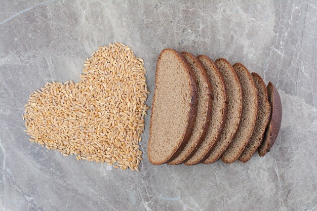 Slices of brown bread with oat grains on marble surface