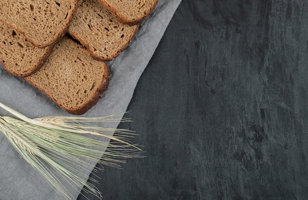 Fette di pane integrale con grano su sfondo grigio.