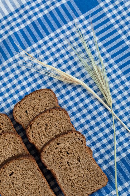 Slices of brown bread with wheat on a tablecloth.