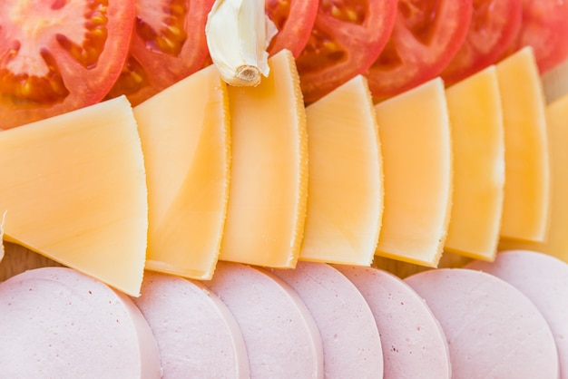 Slices of cheese near tomatoes and lunch meat
