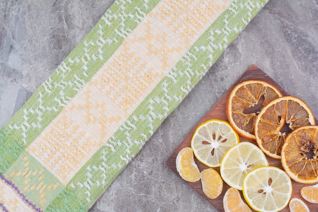 Slices of citrus fruits on wooden board with tablecloth. 
