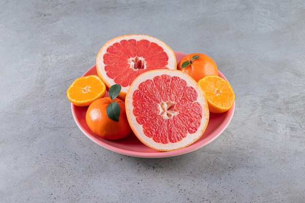 Slices of citrus orange and grapefruit fruits placed on a plate.