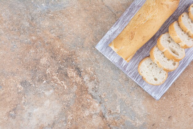 Slices of fresh baguette on wooden board