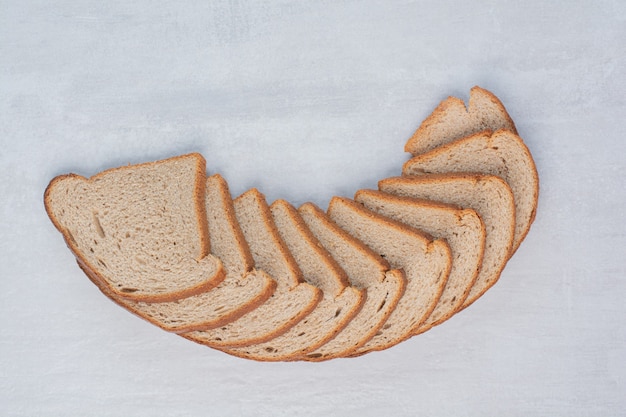 Free photo slices of fresh brown breads on marble background.