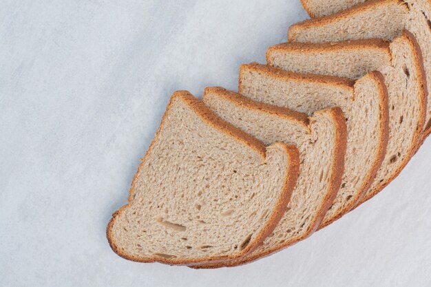 Slices of fresh brown breads on marble background.