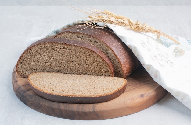 Slices of fresh brown breads on tablecloth .