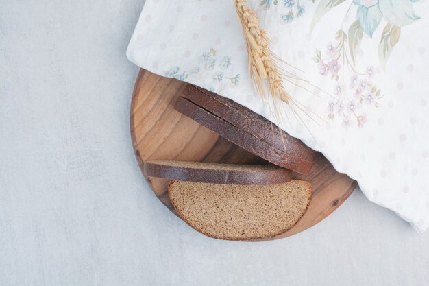 Slices of fresh brown breads on tablecloth .