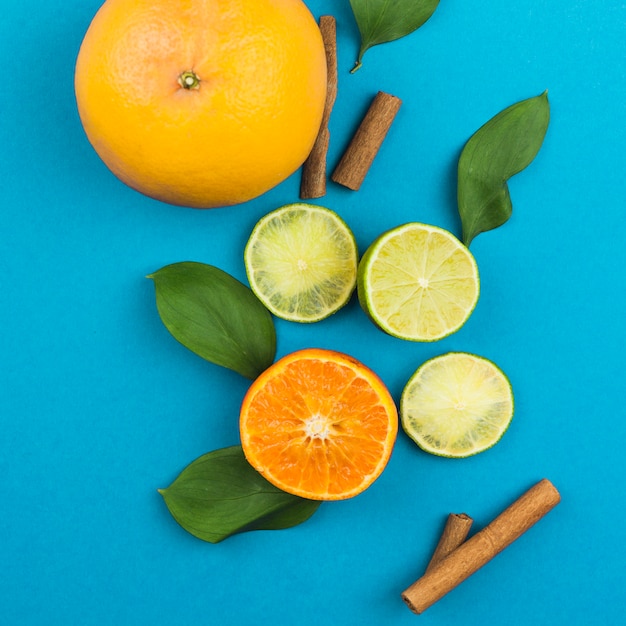 Slices of fresh exotic fruits near cinnamon and foliage