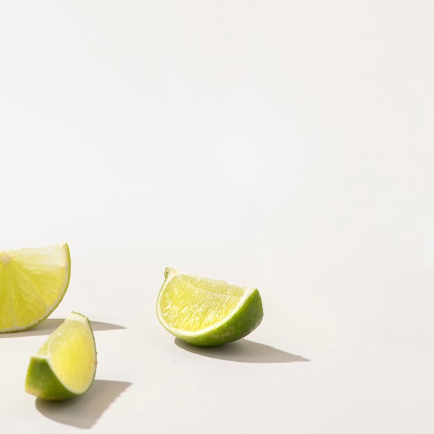 Slices of fresh green lime on white table