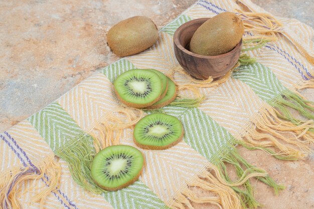 Slices of fresh kiwi on colorful tablecloth. 