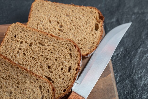 Slices of fresh loaf of bread on wooden board.