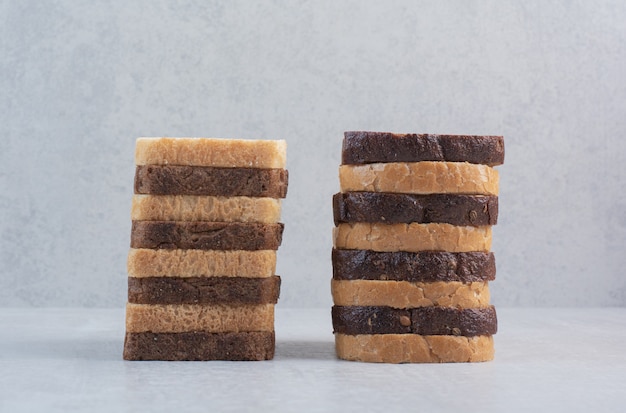 Slices of fresh white and brown breads on marble background.