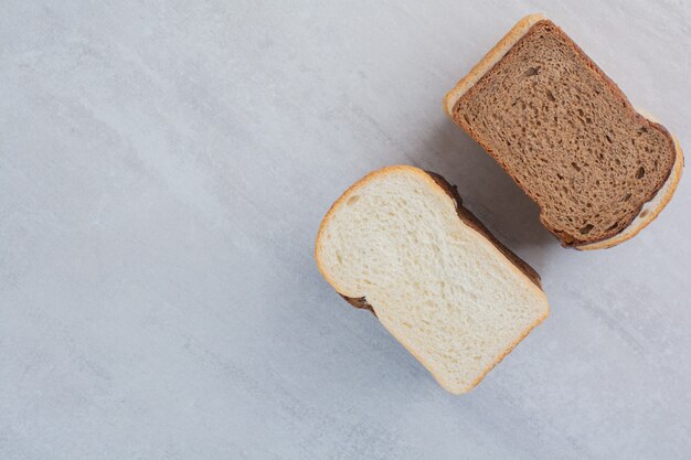 Slices of fresh white and brown breads on marble background.