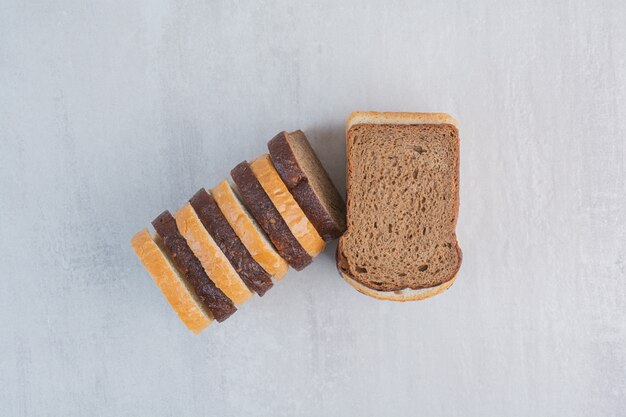 Slices of fresh white and brown breads on marble background.