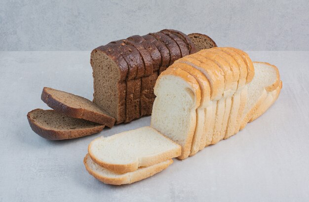 Slices of fresh white and brown breads on marble background.