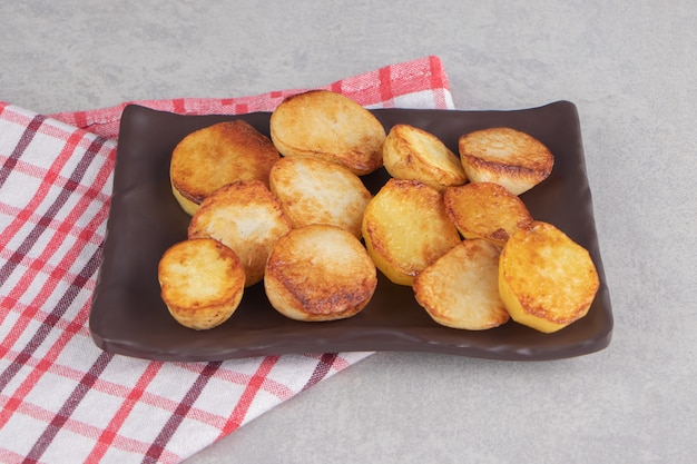 Slices of fried potatoes on brown plate.